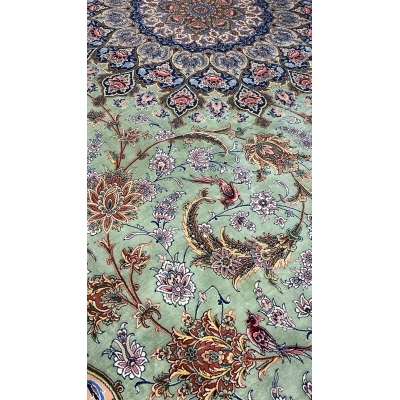 "Close-up of the light green silk field and detailed floral motifs on the Persian rug."