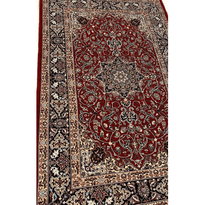 "Close-up of a hand-knotted Seirafian Persian rug, showcasing intricate floral and medallion designs in red, blue, and beige, made from silk and wool."