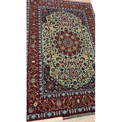 "Detailed view of a luxurious Seirafian Persian rug with silk and wool, featuring vibrant floral patterns on a light green background, hand-knotted in Isfahan."