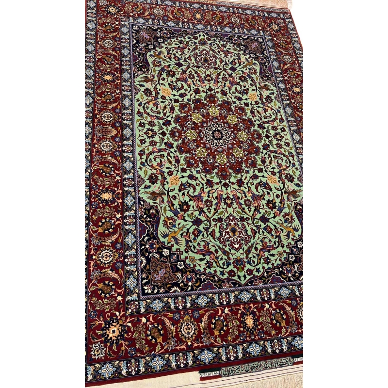 "Detailed view of a luxurious Seirafian Persian rug with silk and wool, featuring vibrant floral patterns on a light green background, hand-knotted in Isfahan."