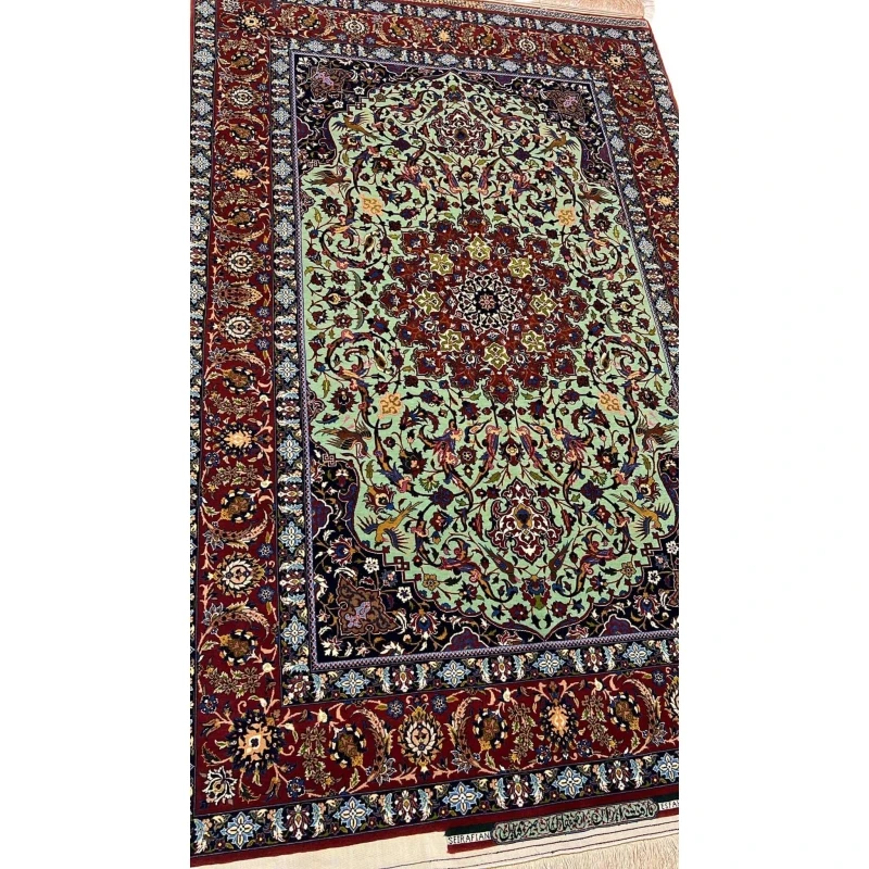 "Detailed view of a luxurious Seirafian Persian rug with silk and wool, featuring vibrant floral patterns on a light green background, hand-knotted in Isfahan."