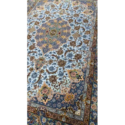 "Close-up of intricate floral designs on a light blue wool and silk Persian carpet."