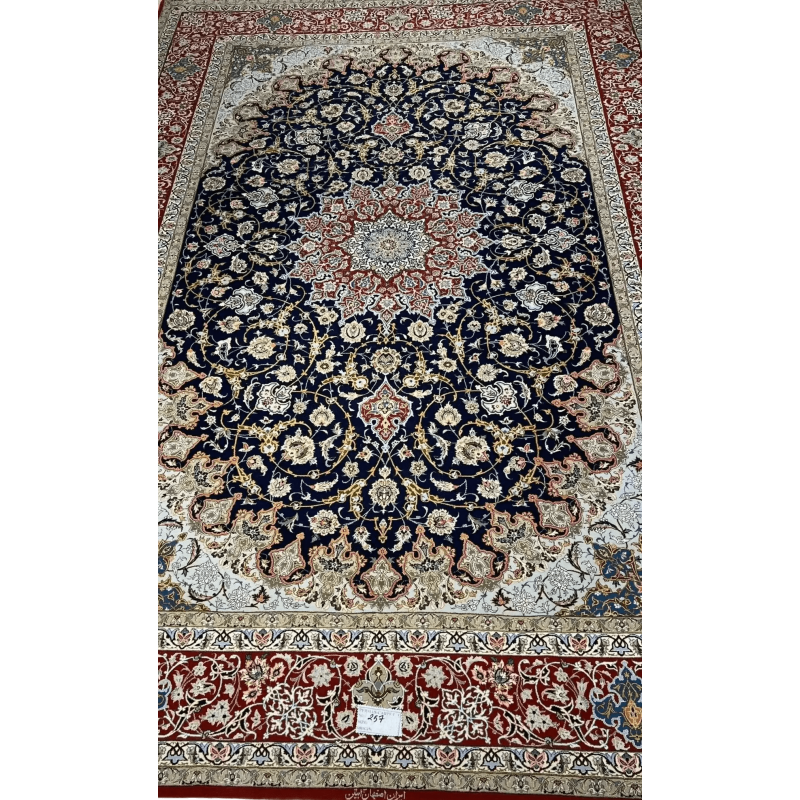 Handmade Persian Carpet from Isfahan – A full view of an elegant Persian carpet with a striking navy-blue field and intricate floral medallion design in red and ivory, hand-knotted with silk and wool by skilled artisans from Isfahan.