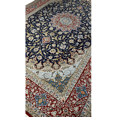 Close-up of Central Medallion on Isfahan Persian Rug – A detailed view of the central medallion on a Persian rug, showcasing vibrant red, blue, and ivory floral motifs, surrounded by intricate curving patterns, meticulously hand-knotted.